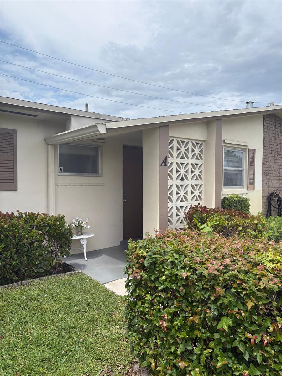The exterior of a single-story residential unit features a covered entryway with decorative breeze blocks — 2522 Emory Drive E # A, West Palm Beach FL 33415, WEST PALM BEACH, FL