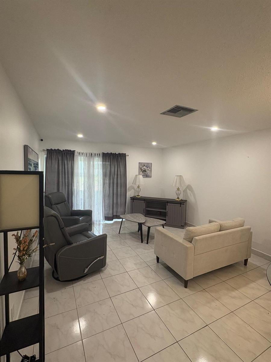 A living room features light tile flooring, a gray recliner, a beige sofa, and curtains — 2522 Emory Drive E # A, West Palm Beach FL 33415, WEST PALM BEACH, FL