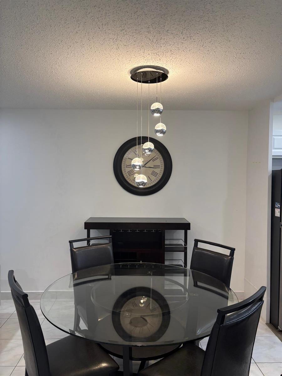 A dining room features a glass-topped table, four black chairs, a wall clock, and pendant lights — 2522 Emory Drive E # A, West Palm Beach FL 33415, WEST PALM BEACH, FL
