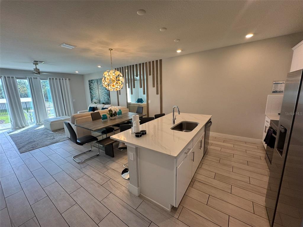 An open-concept kitchen with a white island and dining area featuring a modern chandelier — 768 DRIVING RANGE COURT, KISSIMMEE, FL