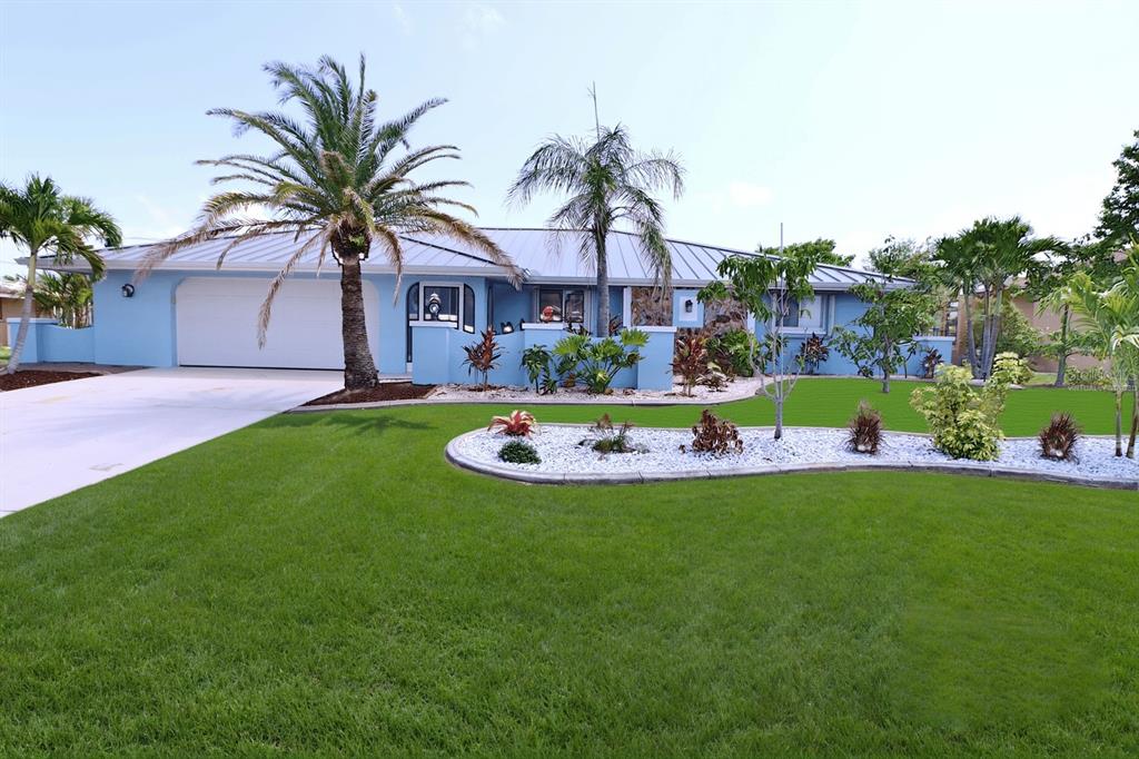 A light blue single-story house with a metal roof and a manicured front lawn — 107 SINCLAIR STREET SE, PORT CHARLOTTE, FL