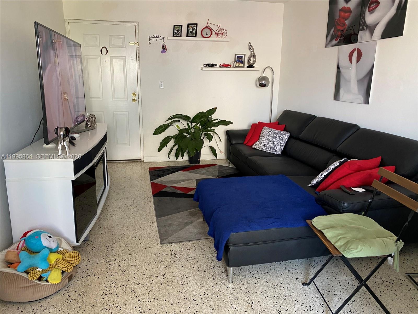 A living room features a black sectional sofa, a television on a stand, and terrazzo flooring — 420 NW 12 Ave # 43, Miami FL 33128, MIAMI, FL