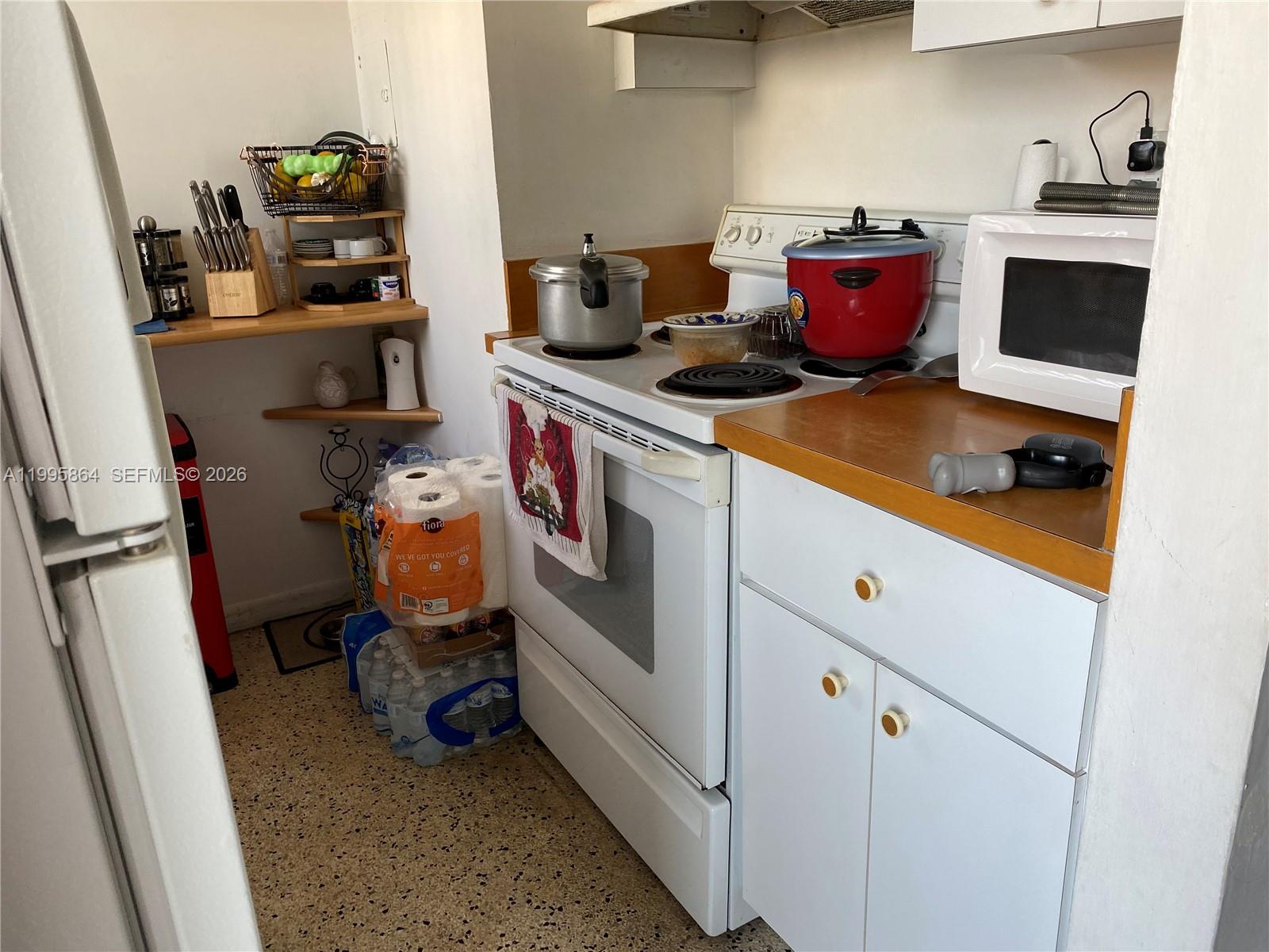 A small kitchen features a white stove, a microwave, and open shelving — 420 NW 12 Ave # 43, Miami FL 33128, MIAMI, FL