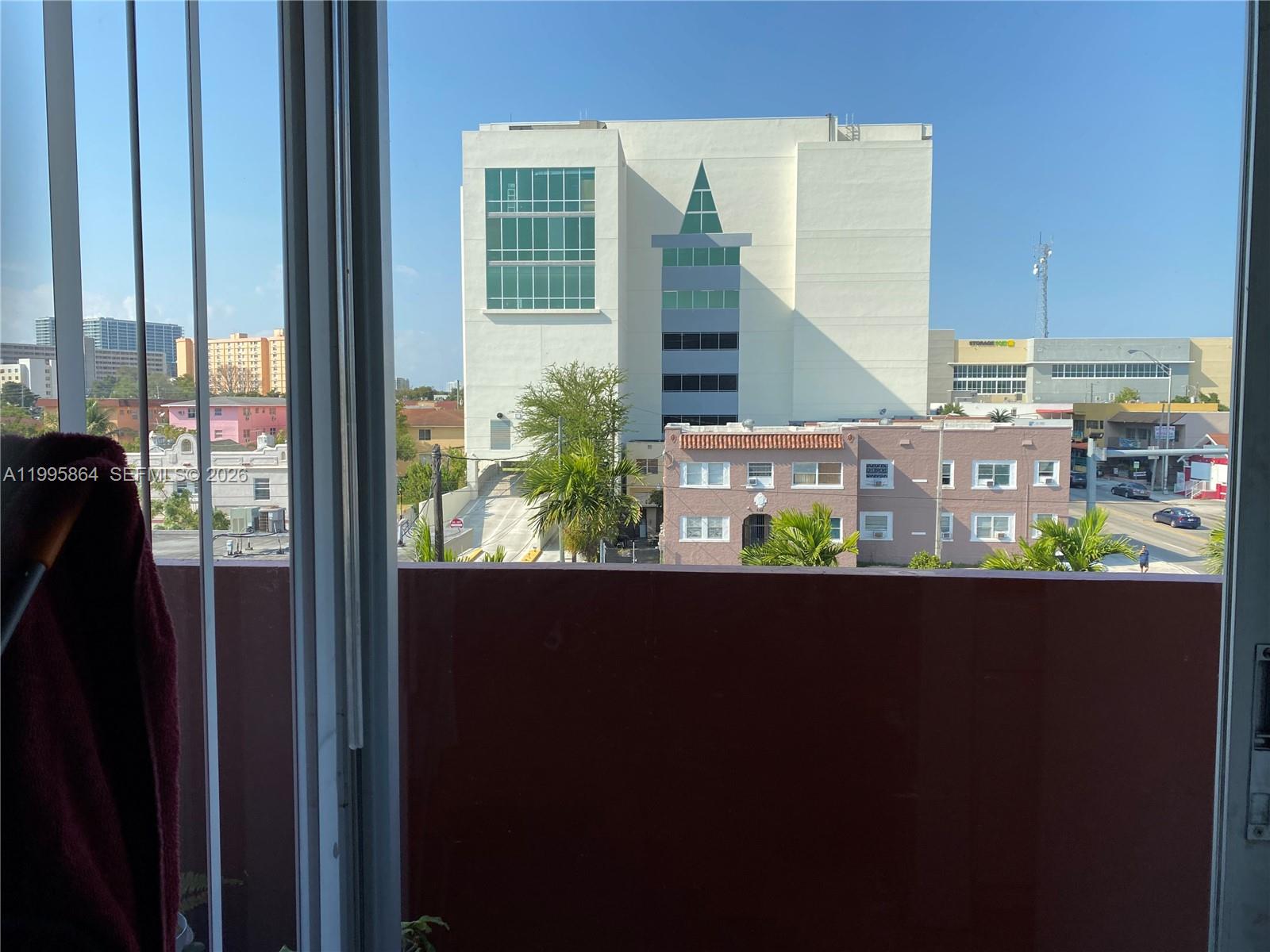 A view from a window shows a city street, low-rise buildings, and a large tower — 420 NW 12 Ave # 43, Miami FL 33128, MIAMI, FL