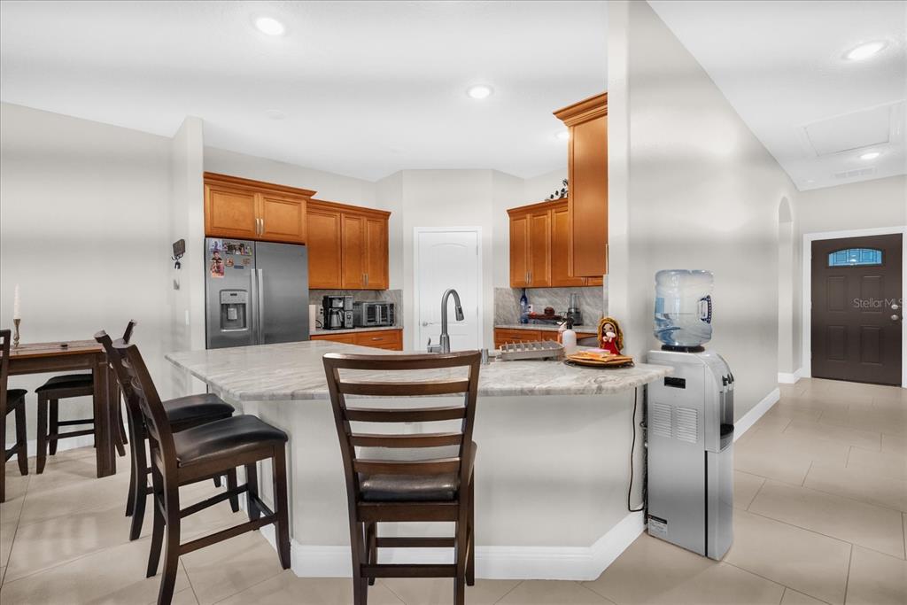 A kitchen with wood cabinets, a granite island, and a water cooler near the entrance — 705 LENOX PLACE, KISSIMMEE, FL