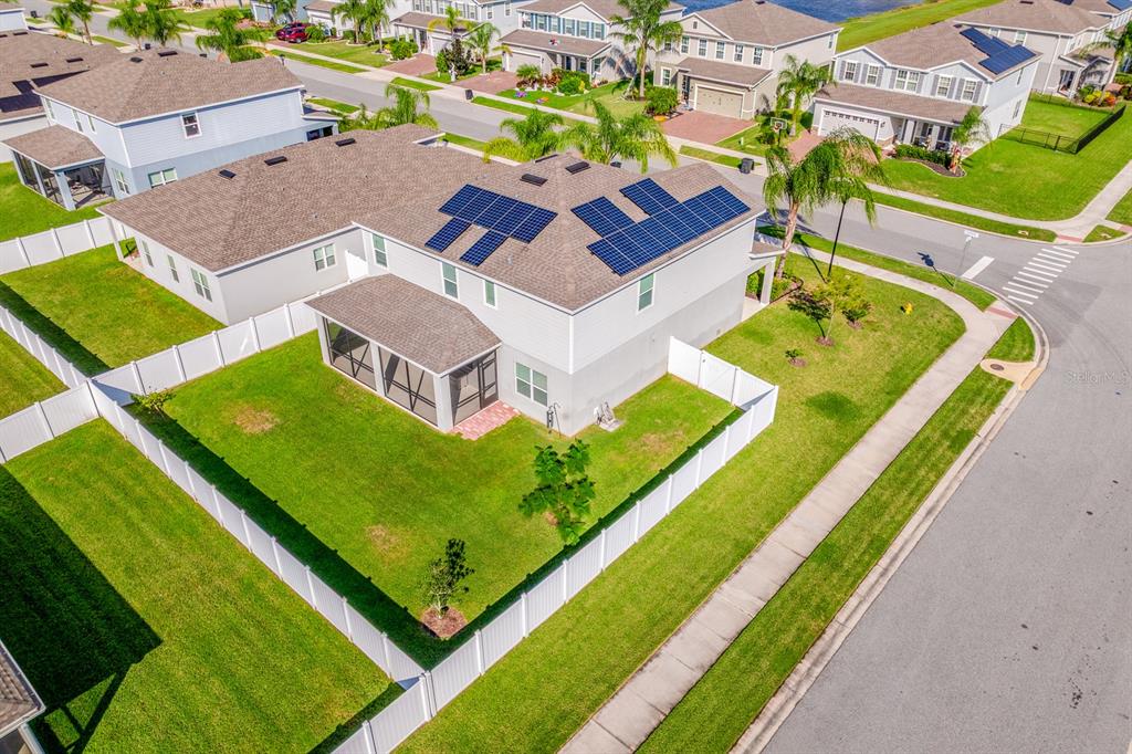 An aerial view shows a two-story house with solar panels on the roof and a yard — 4000 CLIPSTONE PLACE, SANFORD, FL