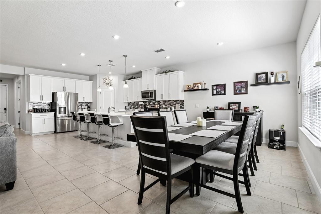 A kitchen with white cabinets and a dining area with a dark wood table — 4000 CLIPSTONE PLACE, SANFORD, FL