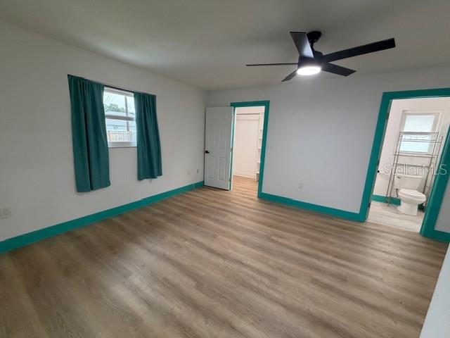 An empty room features light wood-look flooring, white walls, and bright teal baseboards — 20167 HOLLAND AVENUE, PORT CHARLOTTE, FL
