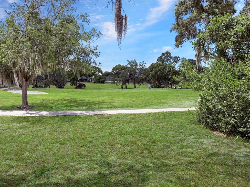 A view of a green golf course fairway with trees and a paved path — 12901 CLUB DRIVE, HUDSON, FL