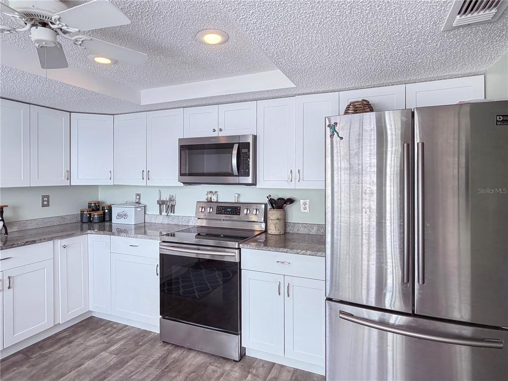 A kitchen features white cabinets, stainless steel appliances, and granite countertops — 12901 CLUB DRIVE, HUDSON, FL
