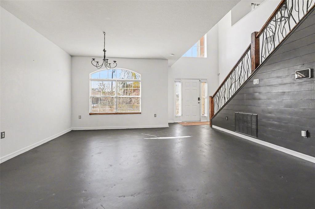 A living room features a grey sectional sofa, wooden coffee table, and a staircase — 548 BIG SIOUX COURT, KISSIMMEE, FL