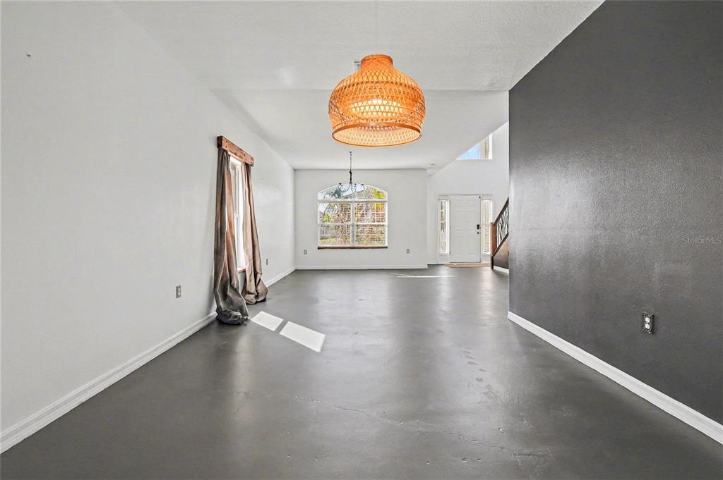 An open entryway and dining area features dark concrete floors, white walls, and a staircase — 548 BIG SIOUX COURT, KISSIMMEE, FL
