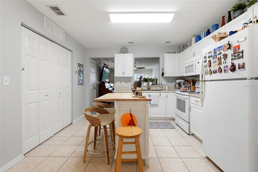 A white kitchen features a central island, tile flooring, and white cabinetry — 4611 SW 48TH WAY UNIT 108, GAINESVILLE, FL