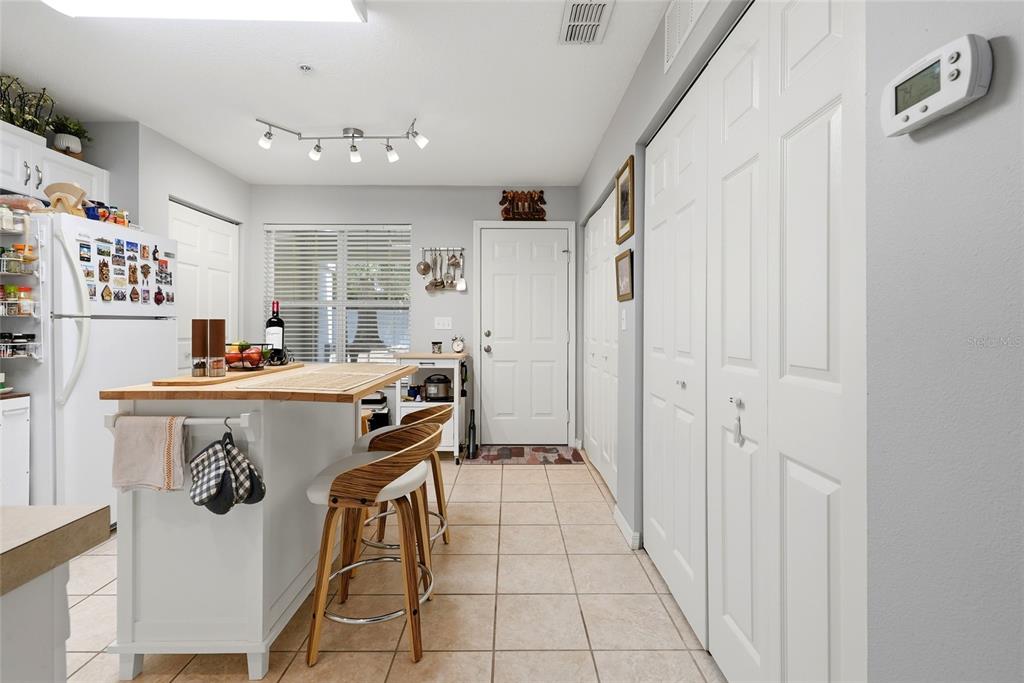 A kitchen features a white island with bar stools, tiled flooring, and white cabinetry — 4611 SW 48TH WAY UNIT 108, GAINESVILLE, FL