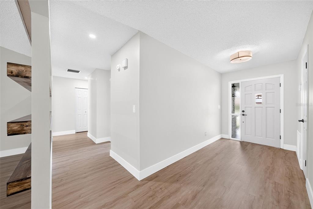 An entryway with light gray walls, wood-look flooring, a white front door, and recessed shelving — 8050 NW 48TH LANE, OCALA, FL