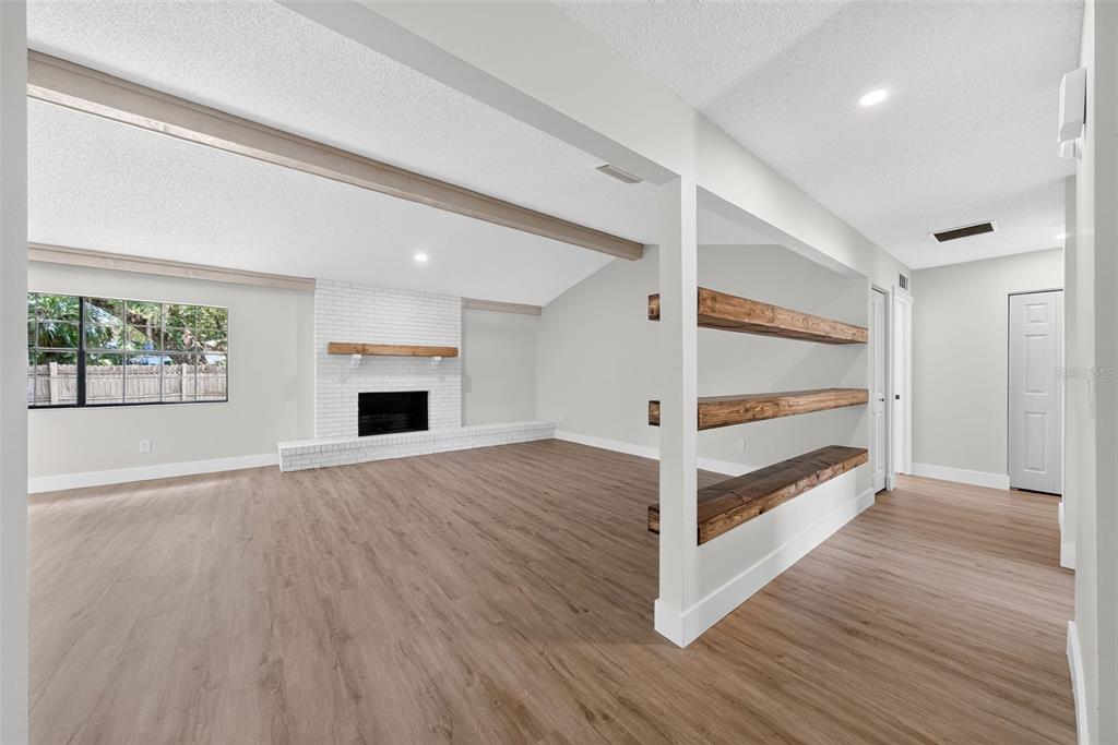 A living room with wood-look flooring, a white brick fireplace, and open wooden shelving — 8050 NW 48TH LANE, OCALA, FL