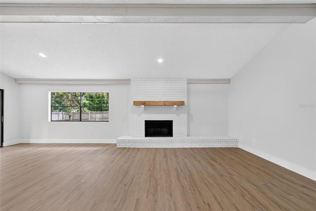 A living room features light wood-look flooring, white walls, and a white brick fireplace — 8050 NW 48TH LANE, OCALA, FL
