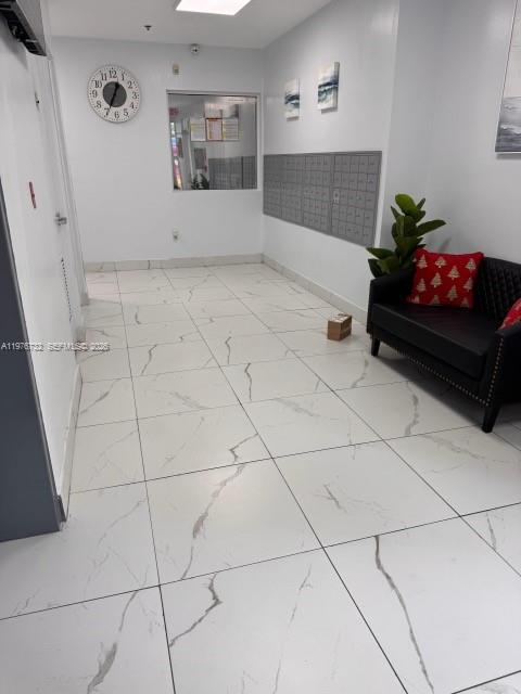 A bright lobby features white marble-look tile flooring, a wall of mailboxes, and a sofa — 104 SW 9th St # 1403, Miami FL 33130, MIAMI, FL