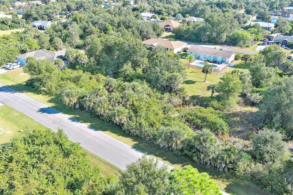 An aerial view shows a residential street bordered by dense vegetation and several houses — 6184 LOMAX STREET, ENGLEWOOD, FL