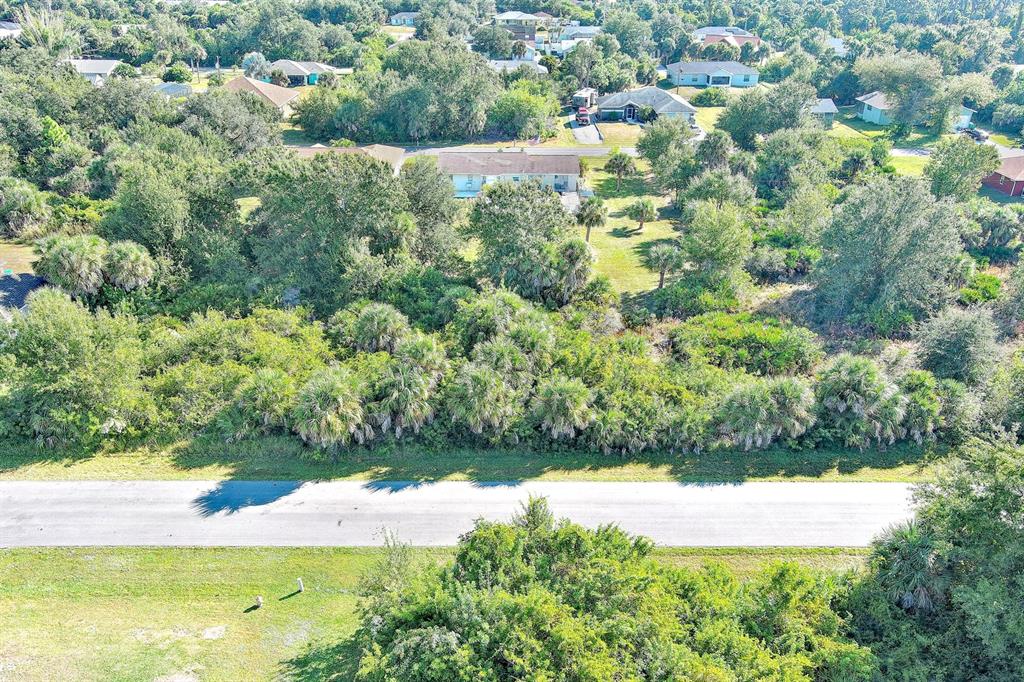 An aerial view shows a vacant, tree-covered lot situated across a road from residential houses — 6184 LOMAX STREET, ENGLEWOOD, FL