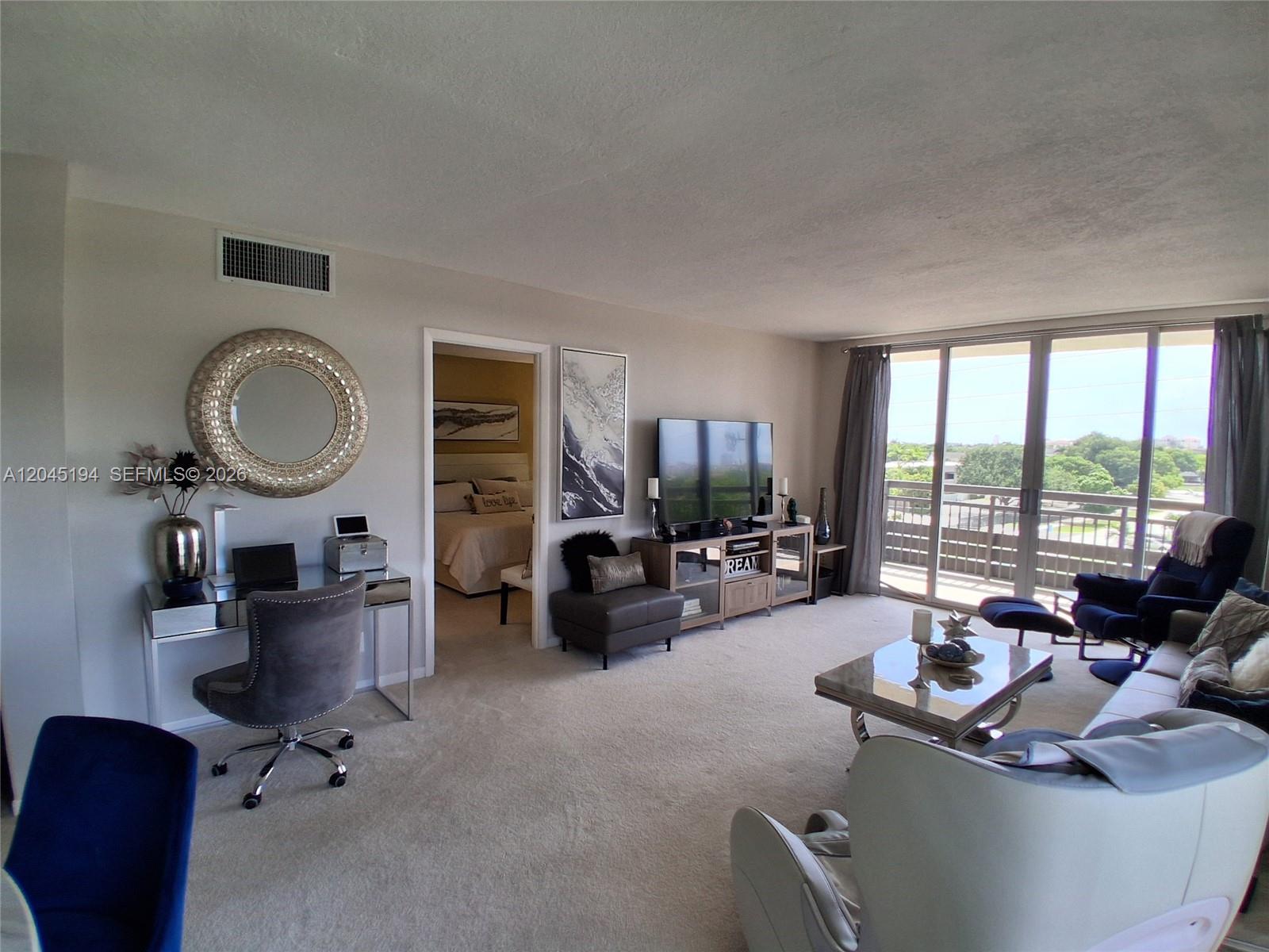 A living room features a desk area, a television console, and a balcony with views — 555 NW 4th Ave # 4250, Boca Raton FL 33432, BOCA RATON, FL