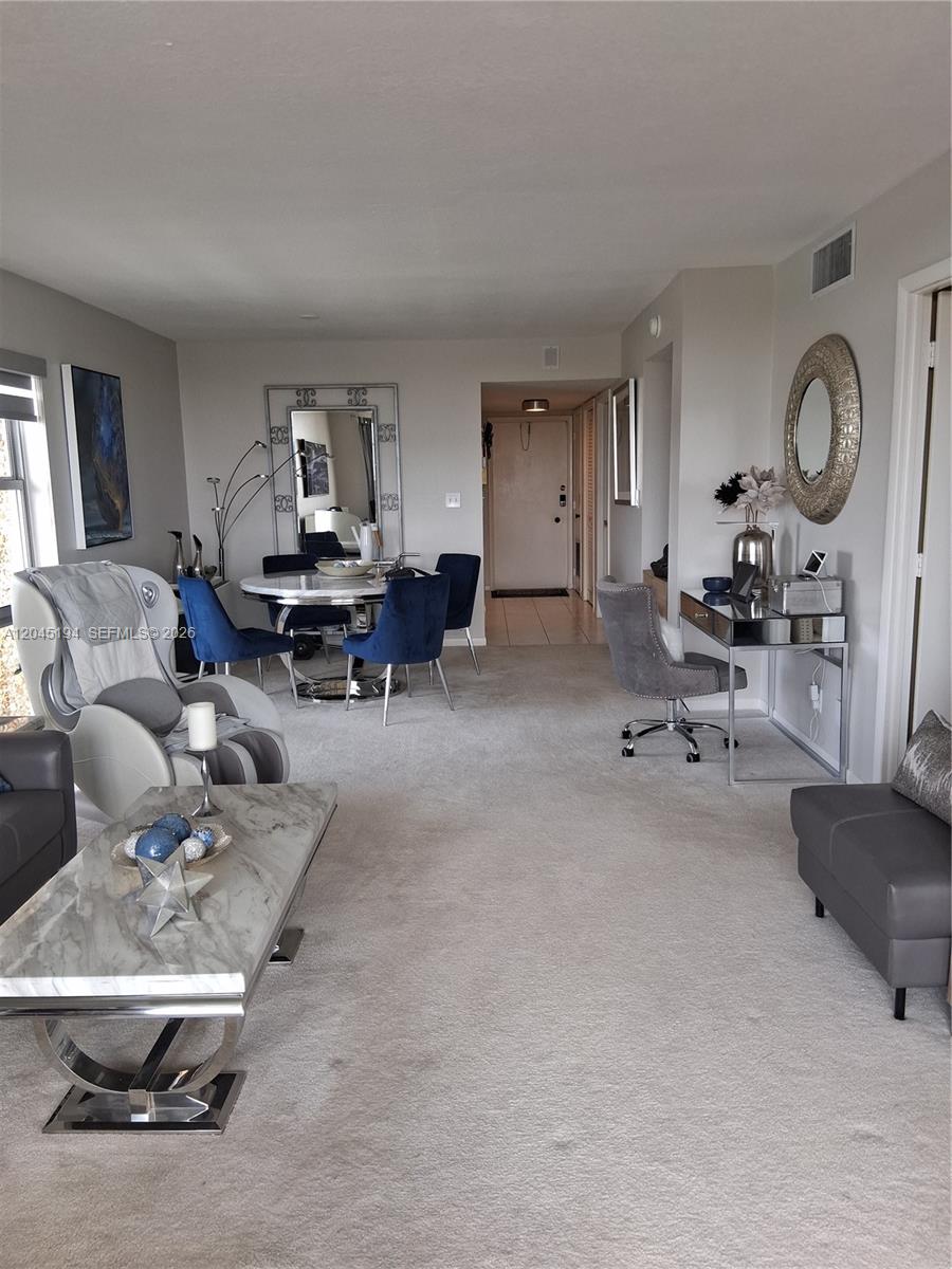 A living room features a dining area, a desk, and a massage chair on carpet — 555 NW 4th Ave # 4250, Boca Raton FL 33432, BOCA RATON, FL