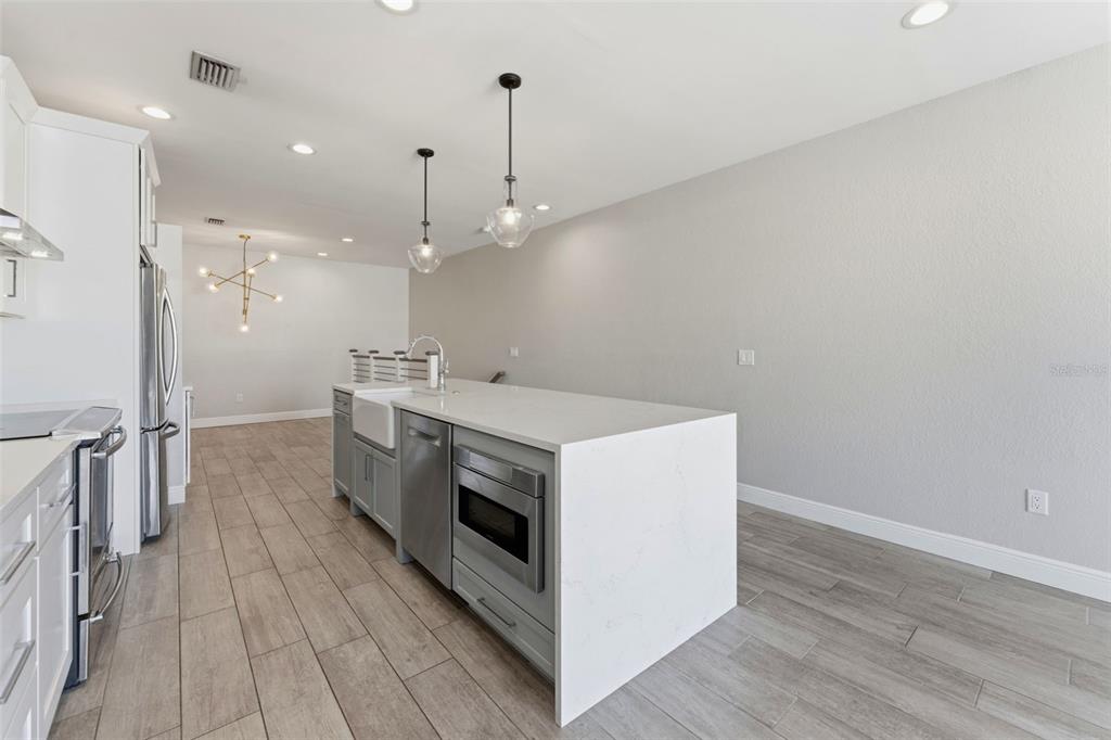 A modern kitchen features a gray island with a built-in microwave, sink, and white countertops — 1022 NORMANDY TRACE ROAD, TAMPA, FL