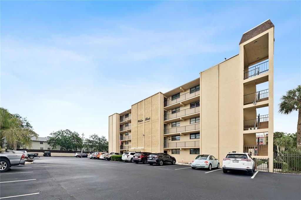 A multi-story apartment building with a parking lot in the foreground — 325 WILDER BOULEVARD UNIT A404, DAYTONA BEACH, FL