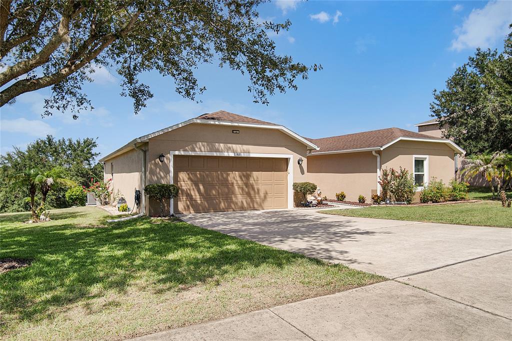 A tan, single-story house with a two-car garage and a concrete driveway — 2388 YELLOW GRASS COURT, APOPKA, FL