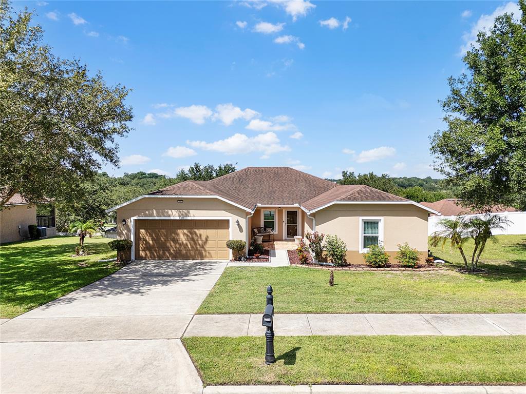 A single-story house with a tan exterior, brown roof, and a two-car garage — 2388 YELLOW GRASS COURT, APOPKA, FL