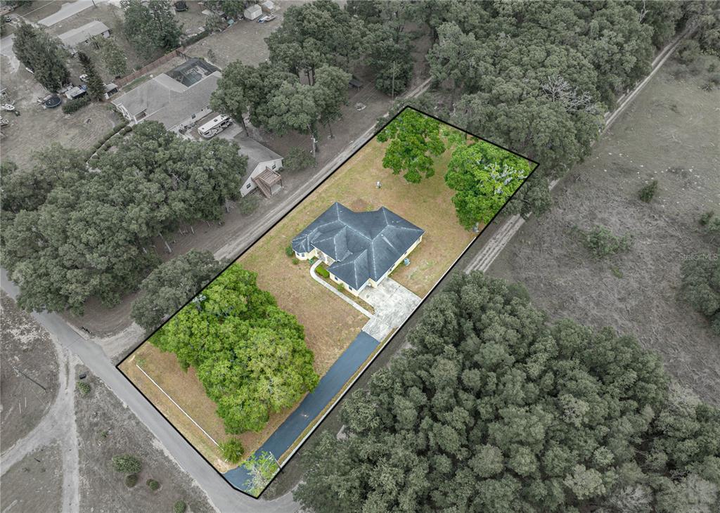 An aerial view shows a single-story house with a dark roof on a wooded lot — 12806 JUDY STREET, DADE CITY, FL