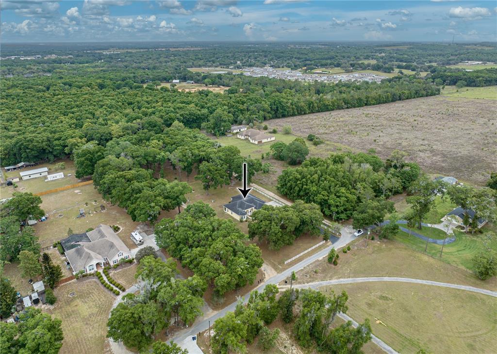 An aerial view shows a house with a dark roof surrounded by trees and fields — 12806 JUDY STREET, DADE CITY, FL