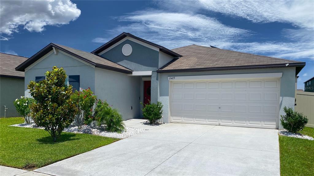 A single-story house with a light-colored exterior, a two-car garage, and a landscaped front yard — 15423 MILLER CREEK DRIVE, RUSKIN, FL