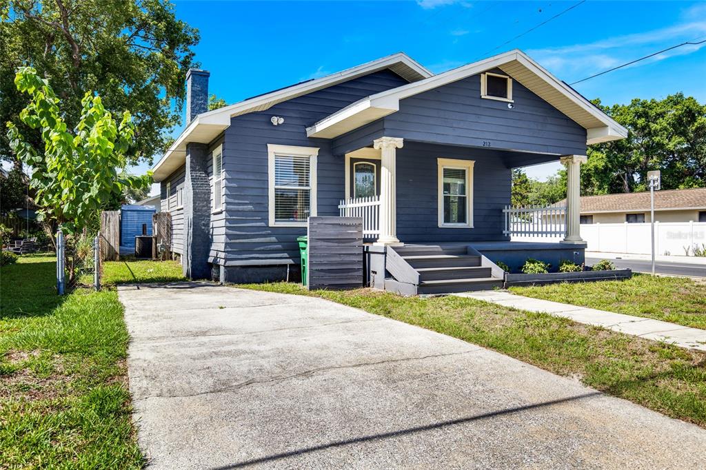 A blue, single-story house with a front porch, concrete driveway, and white trim — 212 W GENESEE STREET, TAMPA, FL