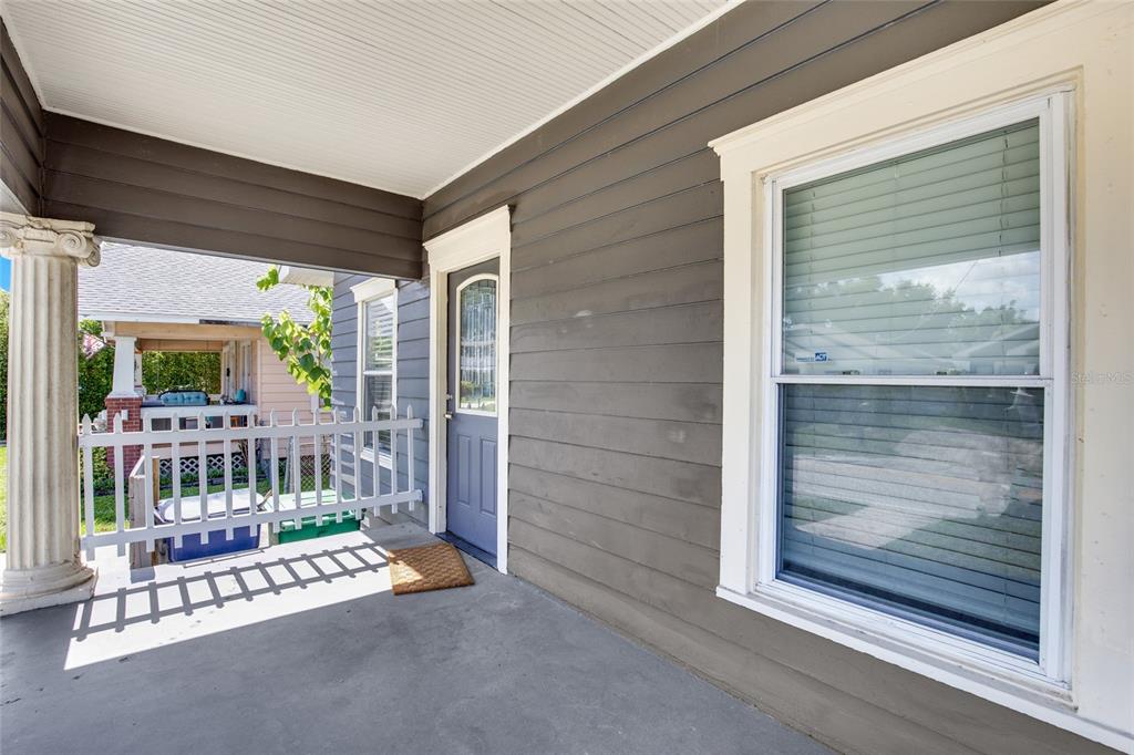 A covered front porch features gray horizontal siding, a blue door, and a white railing — 212 W GENESEE STREET, TAMPA, FL