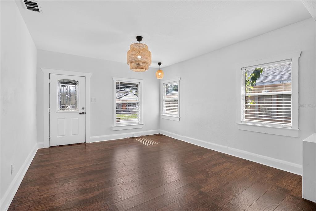 An empty room with dark wood floors, white walls, two pendant lights, and three windows — 212 W GENESEE STREET, TAMPA, FL