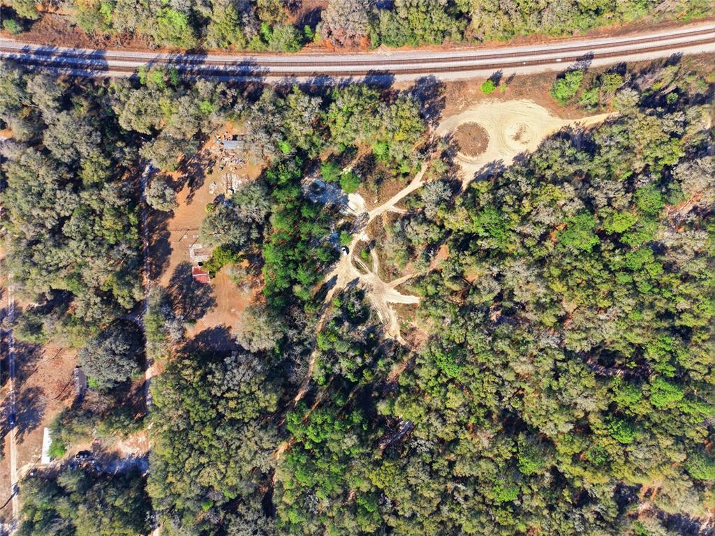 An aerial view shows a wooded lot with dirt paths, a small structure, and railroad tracks — Lot 026 NE 164TH LANE, CITRA, FL