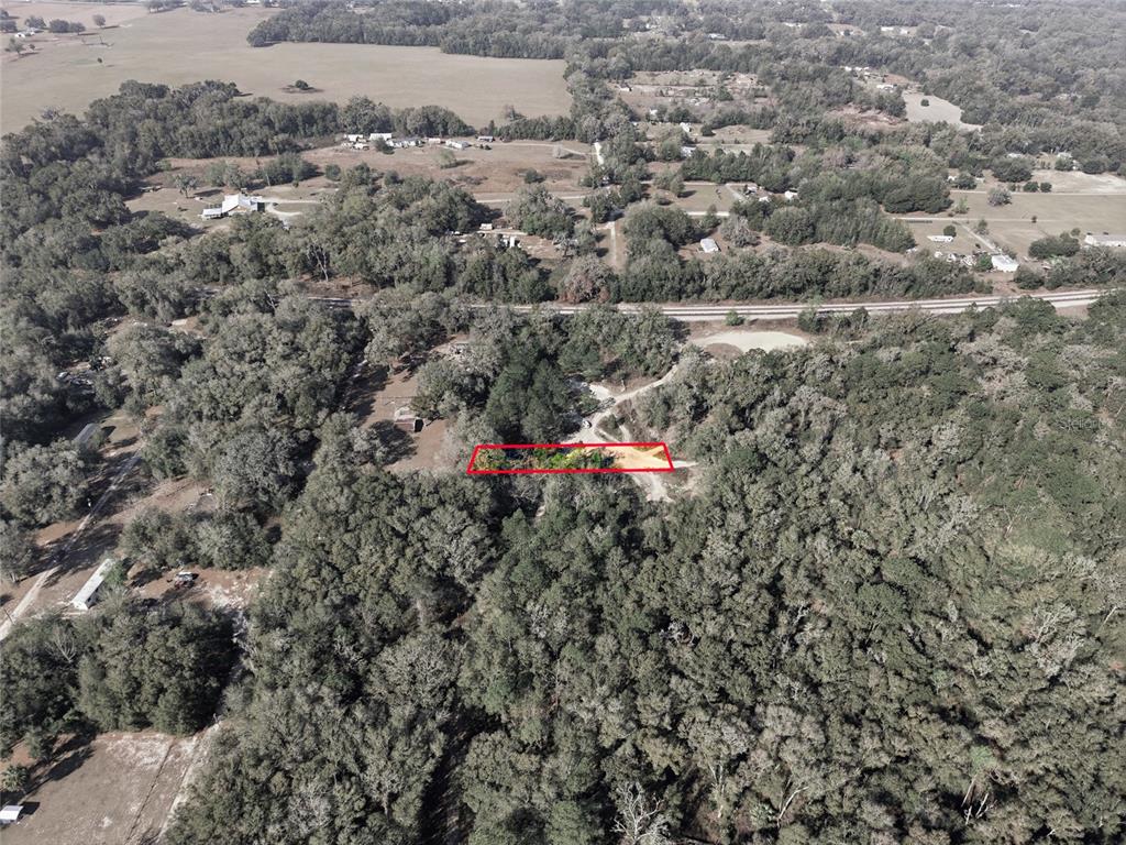 An aerial view shows a rectangular plot of land outlined in red amidst dense woods — Lot 026 NE 164TH LANE, CITRA, FL