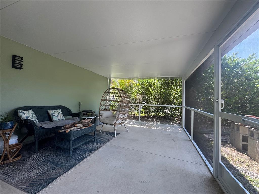 A screened-in patio features a wicker sofa, an egg chair, and a concrete floor — 21239 COTTONWOOD AVENUE, PORT CHARLOTTE, FL