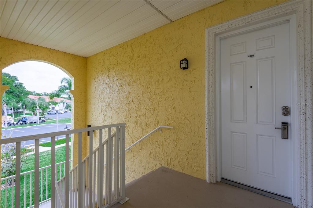 A yellow exterior wall with a white door labeled C206 next to a metal staircase — 6750 DALI AVENUE UNIT 206, LAND O LAKES, FL