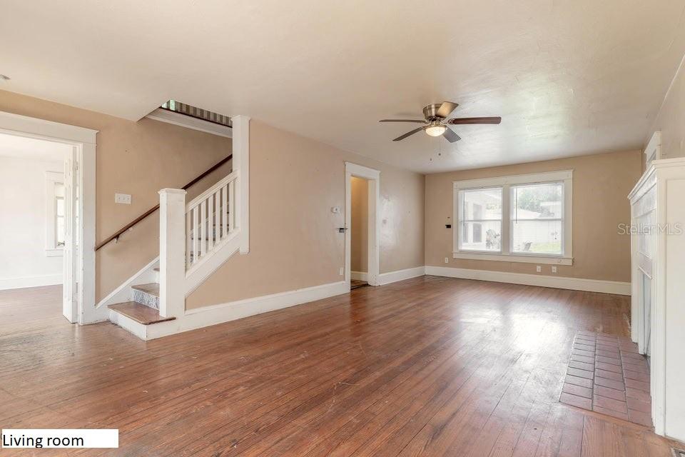 A living room features hardwood floors, a staircase with a white railing, and a ceiling fan — 724 N OLEANDER AVENUE, DAYTONA BEACH, FL