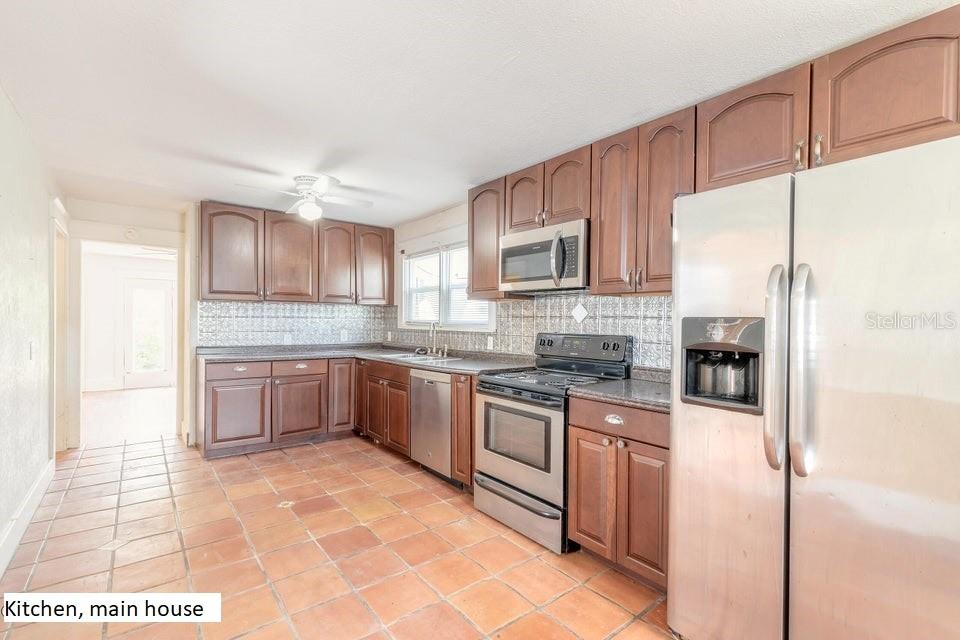 A kitchen with wood cabinets, stainless steel appliances, and terracotta tile flooring — 724 N OLEANDER AVENUE, DAYTONA BEACH, FL