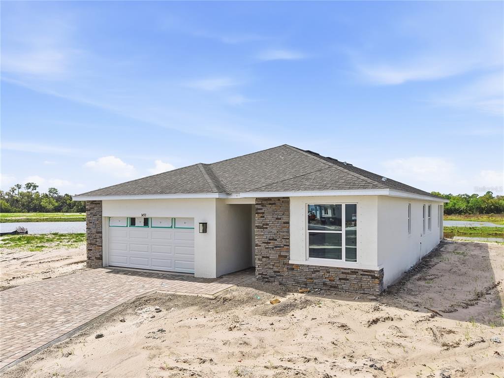 A newly constructed single-story house with a stone facade, garage, and paved driveway — 14511 BANKS COURT, PARRISH, FL