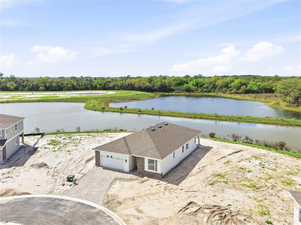 An aerial view shows a newly constructed single-story house situated next to a large pond — 14511 BANKS COURT, PARRISH, FL