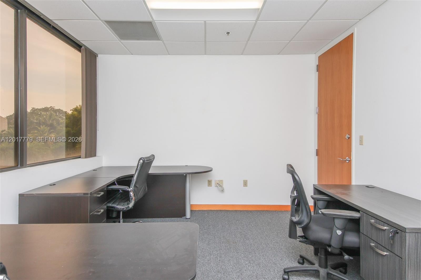 An office space features two desks, two chairs, a window, and a wooden door — 1900 Glades Rd # 276, Boca Raton FL 33431, BOCA RATON, FL