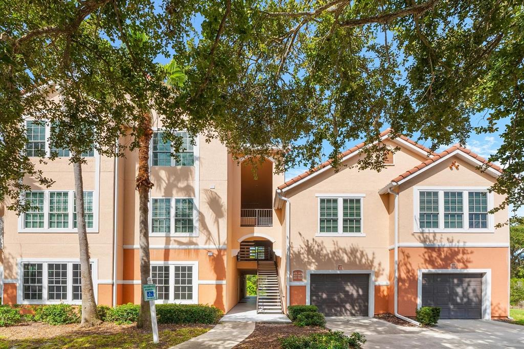 A two-story apartment building with a peach-colored stucco exterior, two garages, and a staircase — 4106 CENTRAL SARASOTA PARKWAY UNIT 1015, SARASOTA, FL