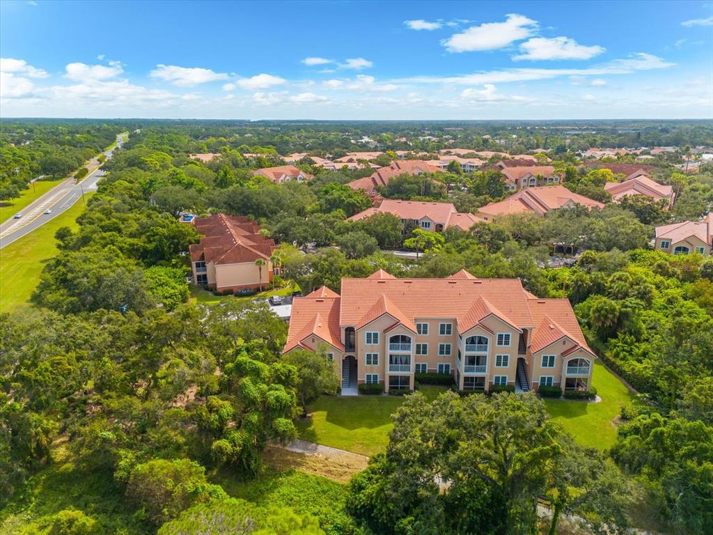 An aerial view shows a multi-story apartment building with a red tile roof — 4106 CENTRAL SARASOTA PARKWAY UNIT 1015, SARASOTA, FL