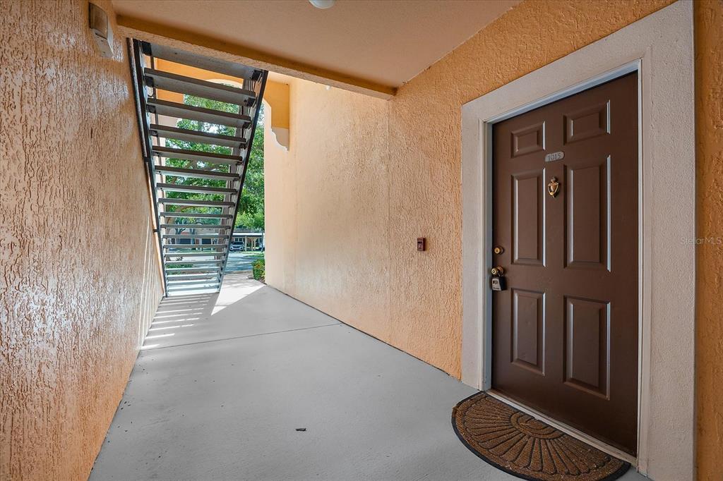An exterior view shows a brown apartment door with a staircase leading to upper levels — 4106 CENTRAL SARASOTA PARKWAY UNIT 1015, SARASOTA, FL