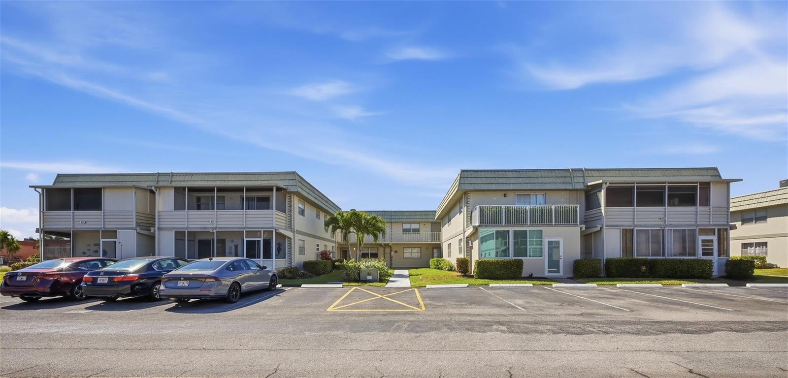 A two-story apartment building with a parking lot in front under a blue sky — 451 Monaco J # j, Delray Beach FL 33446, DELRAY BEACH, FL
