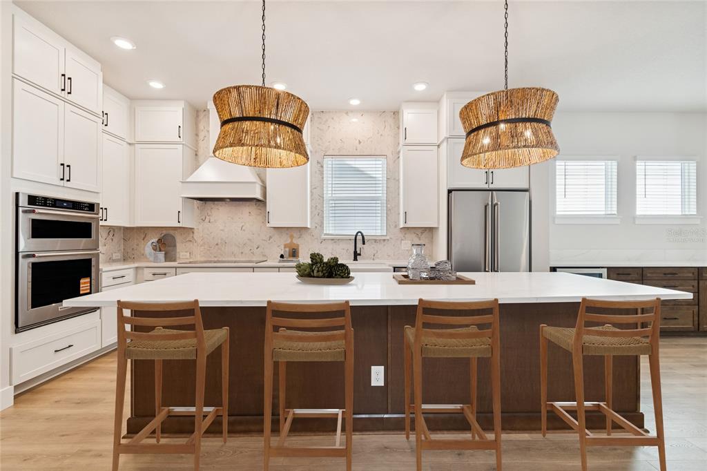 A modern kitchen features a large dark wood island, white cabinetry, and two woven pendant lights — 1104 W OHIO AVENUE, TAMPA, FL